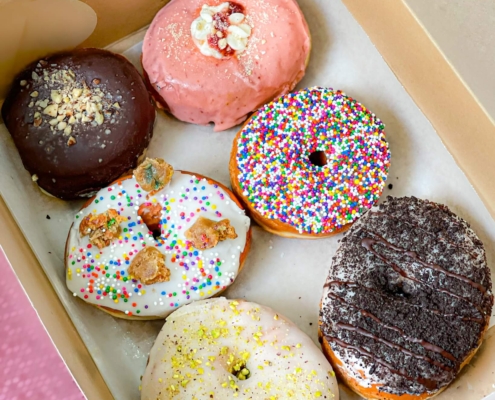 Six vegan sprinkle donuts in a box